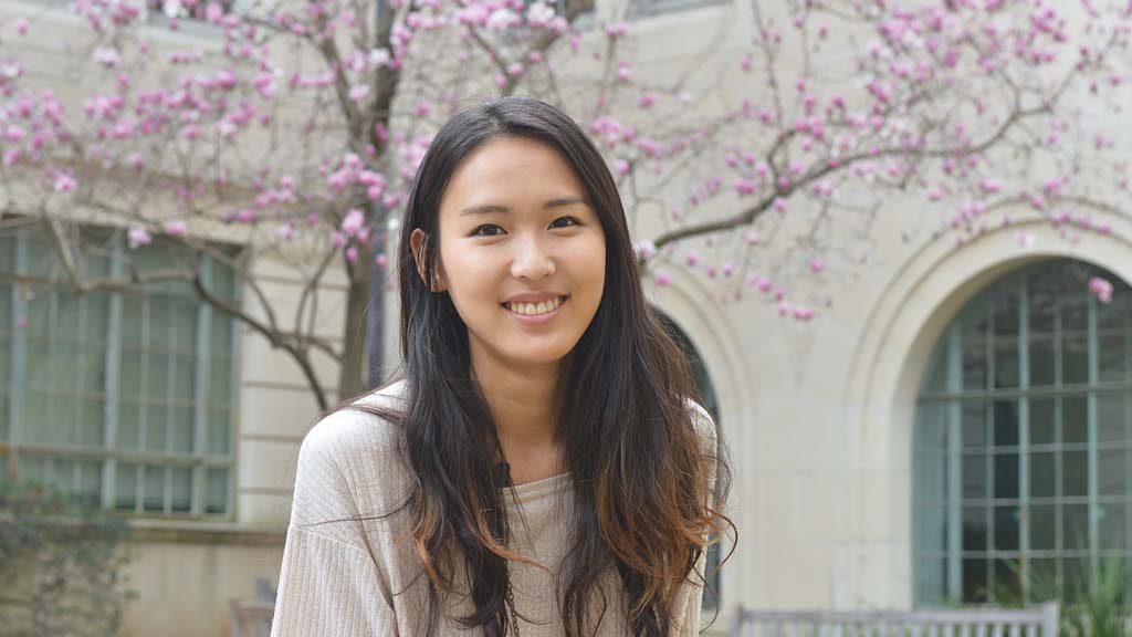 A woman smiling in front of a flowering tree.