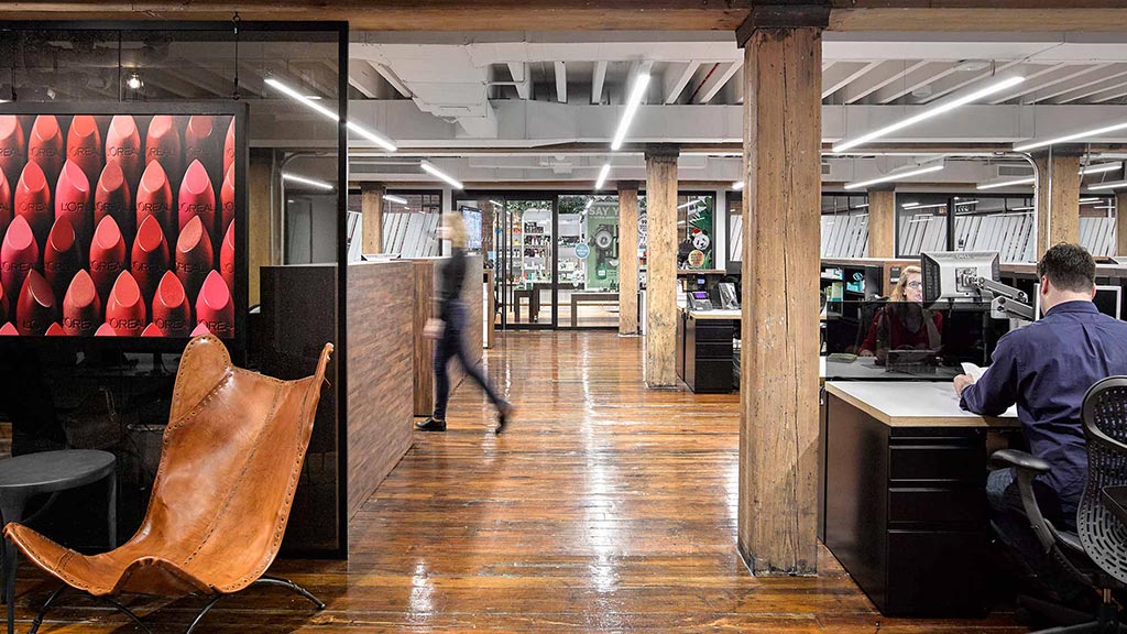 A person sitting at a desk in a large room with a large wood floor and a large wood.