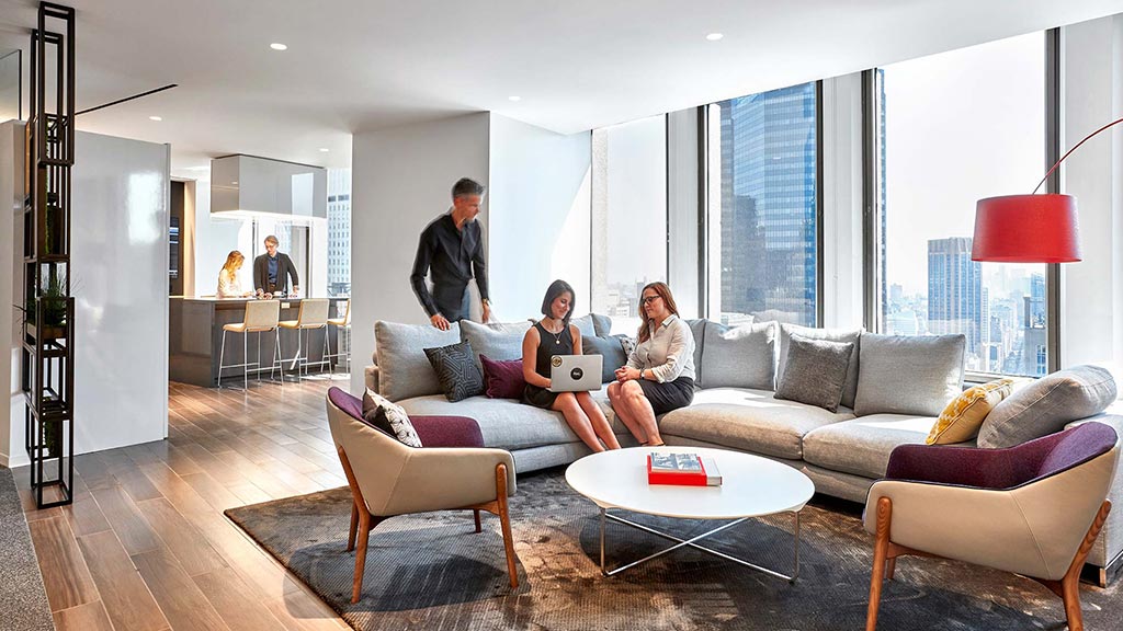 A group of people sitting on a couch with a laptop.