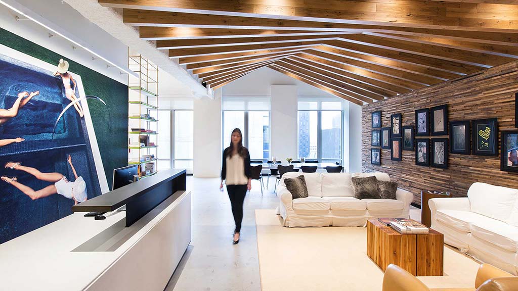 A person standing in a room with a large window and a couch.