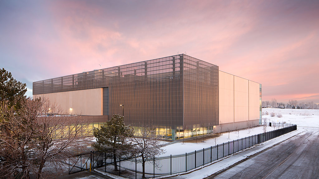 A building with a road and trees in front of it.