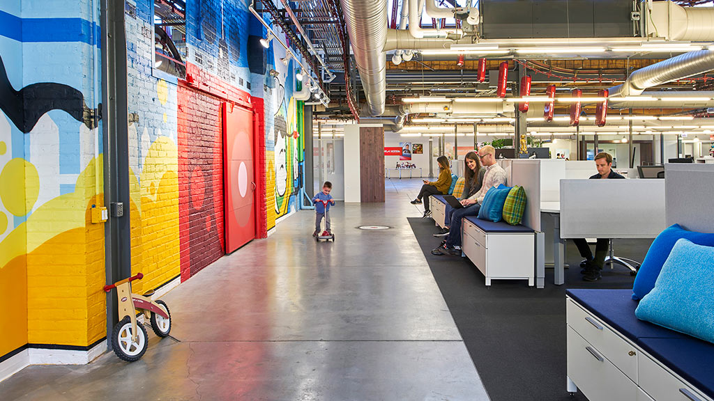 A group of people sitting at a table in a room with colorful walls.