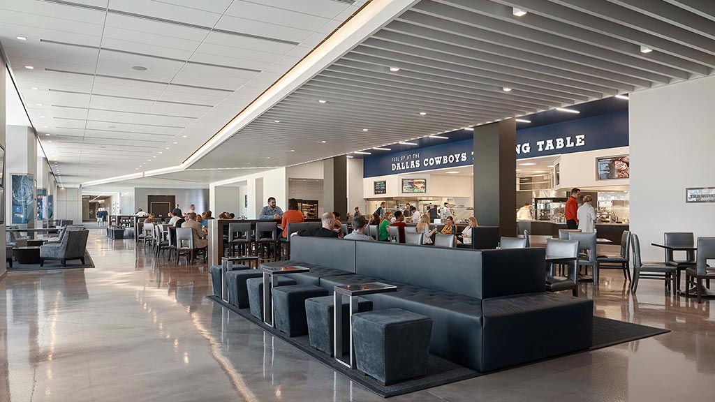 A group of people in a large room with tables and chairs.