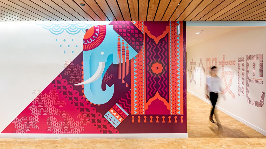 A person walking in a room with a large piece of art.