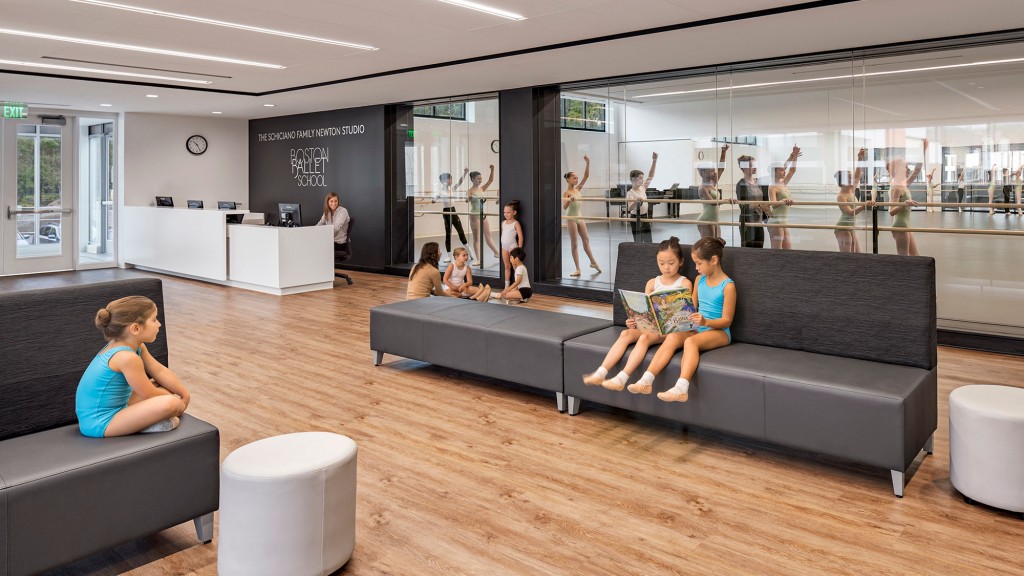 A group of people sitting on a couch in a room with a large screen.