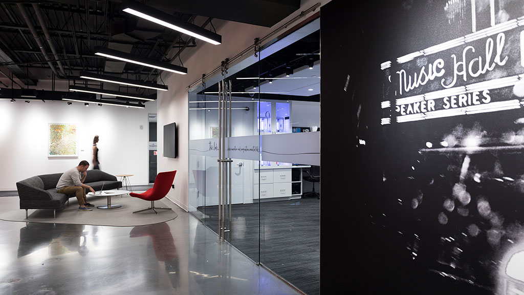 A person sitting on a couch in a room with a large screen.