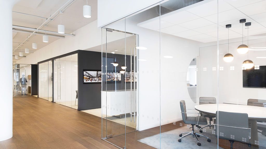 A room with a glass door and a glass wall with chairs.