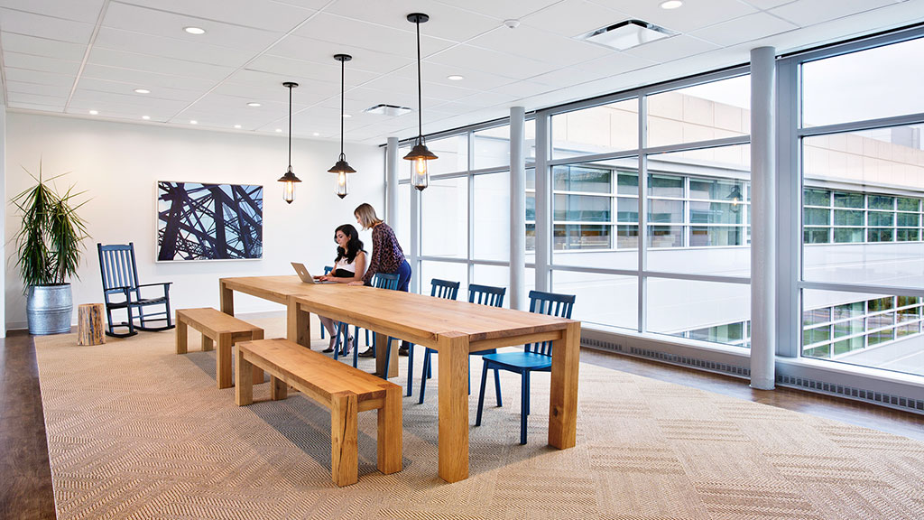 A couple of people sitting at a table in a room with windows.