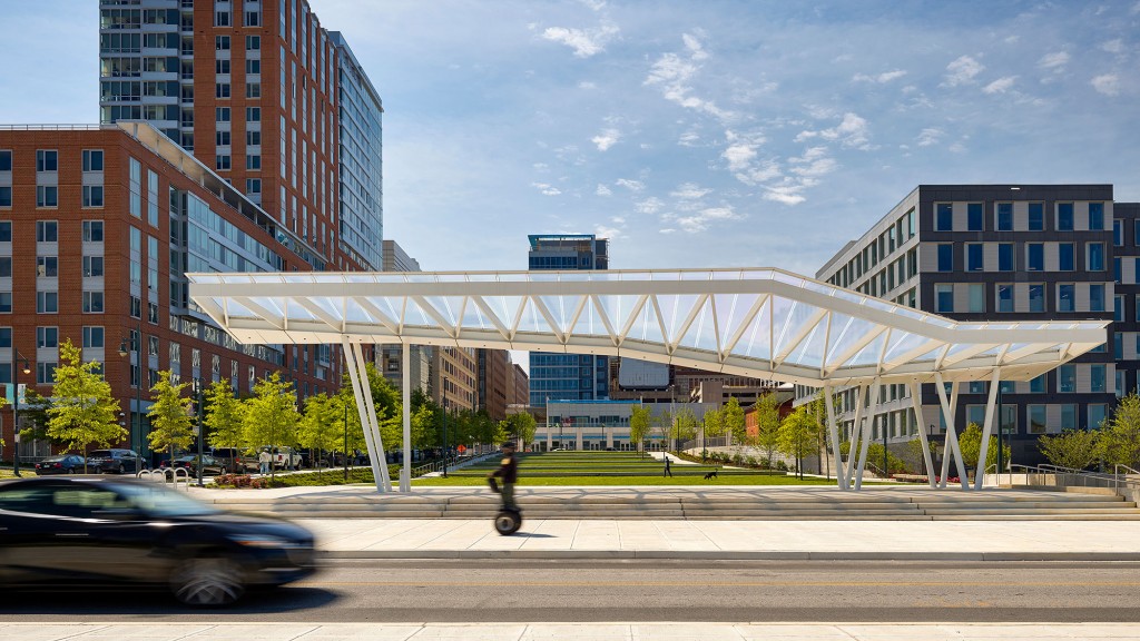 A person riding a scooter on a street with buildings in the background.