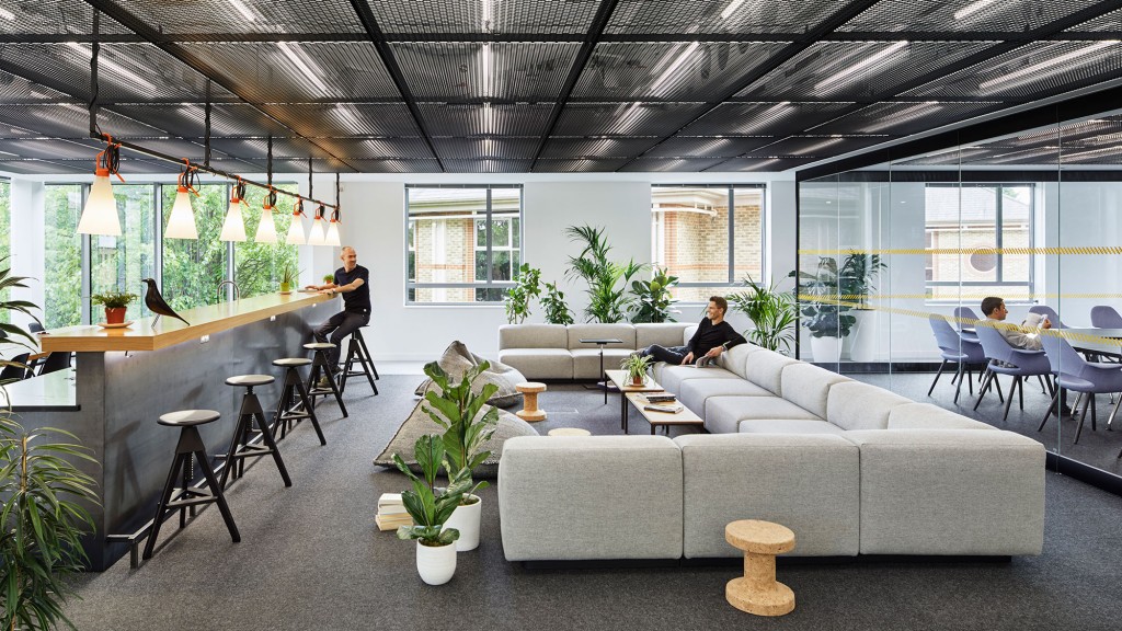 A person sitting on a couch in a room with tables and chairs.