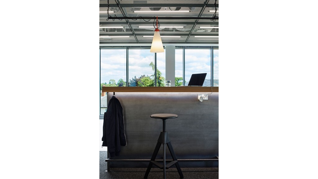 A desk with a laptop and a chair in a room with windows.
