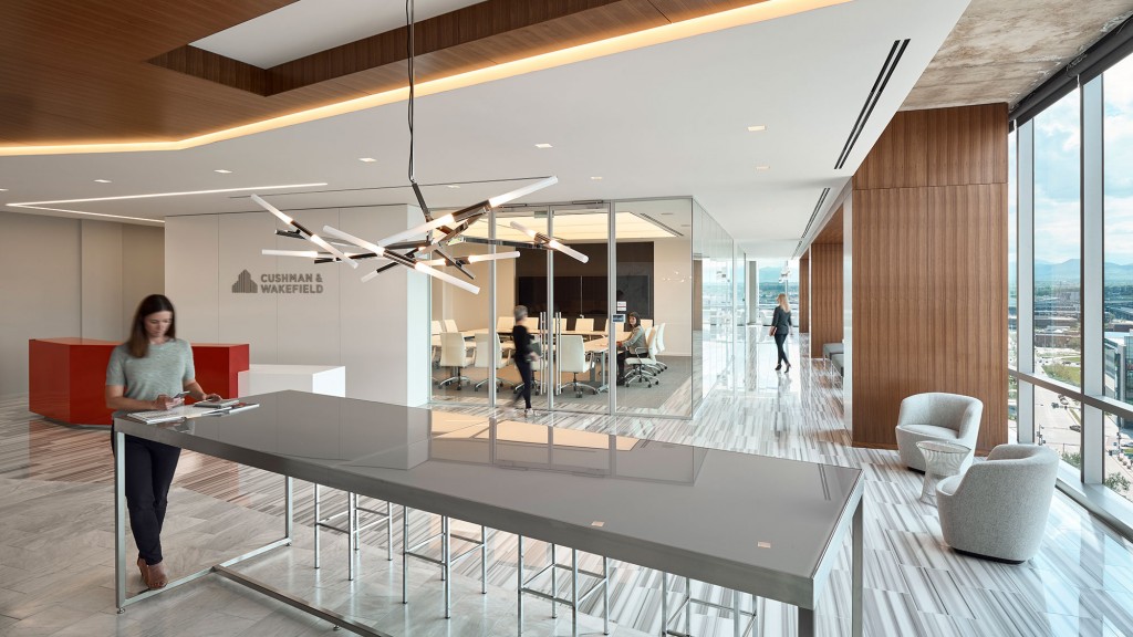 A person standing in a room with a glass table and chairs.