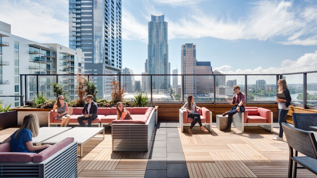 A group of people sitting on a deck with a city skyline in the background.