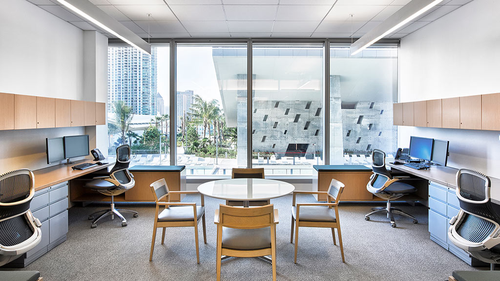 A room with a table chairs and a window with a view of the city.