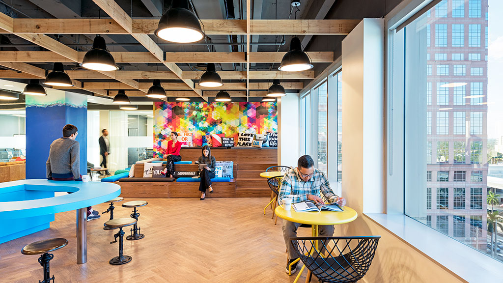 A group of people sitting at tables in a room with a large window.
