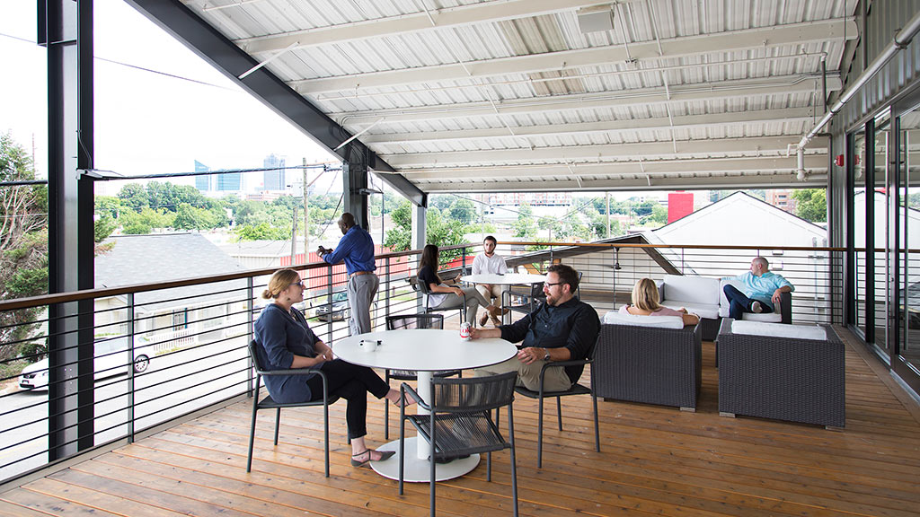 A group of people sitting around a table on a deck.