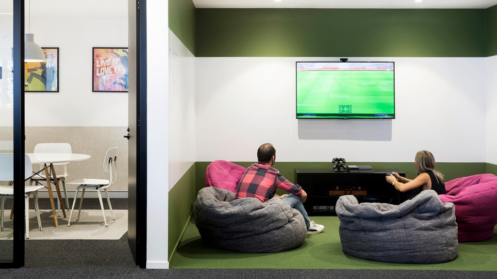 A man and a woman sitting on a couch watching a projector screen.
