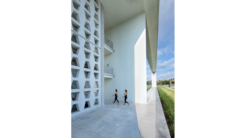 A couple of people walking down a corridor between white buildings.