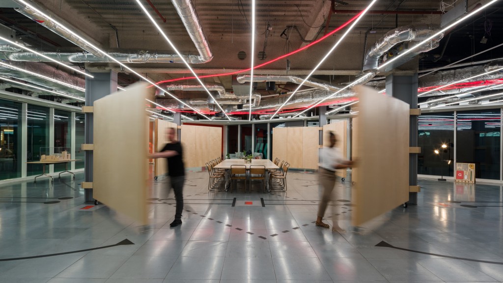 A man and a woman walking in a large room with tables and chairs.