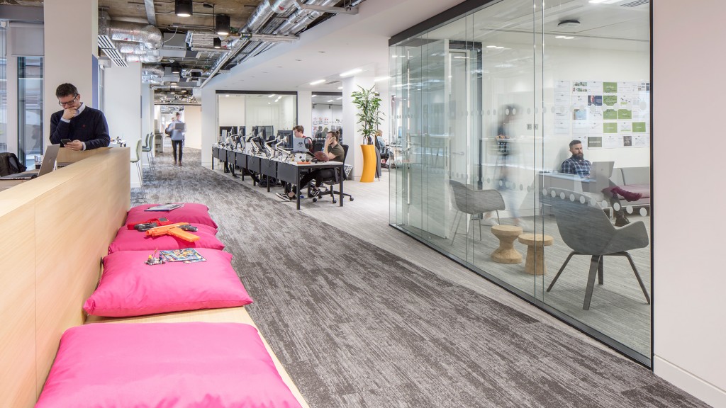 A room with a bed and a table with a couple of people.