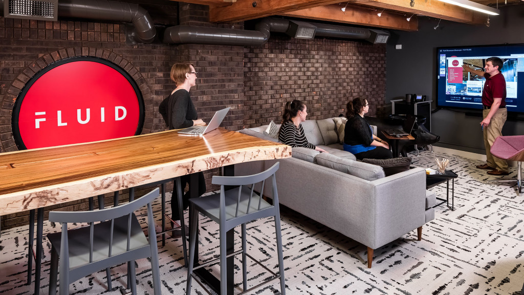 A group of people sitting at a table with a laptop.
