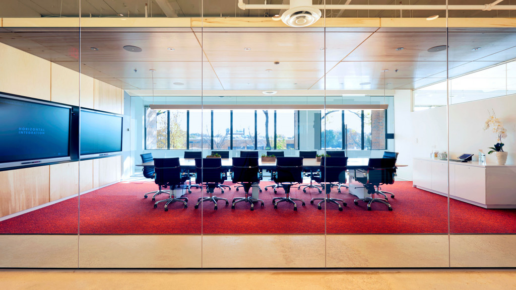 A room with a red carpet and a large window with a view of the city.