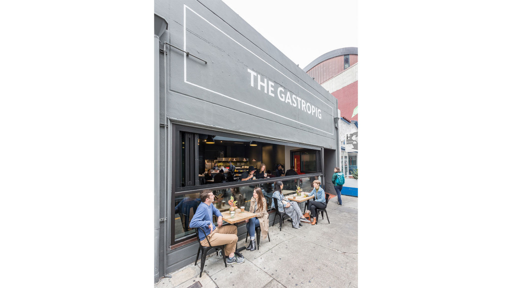 A group of people sitting at a table in front of a restaurant.