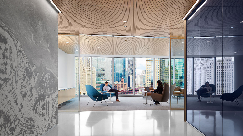 A group of people sitting in a room with large windows.