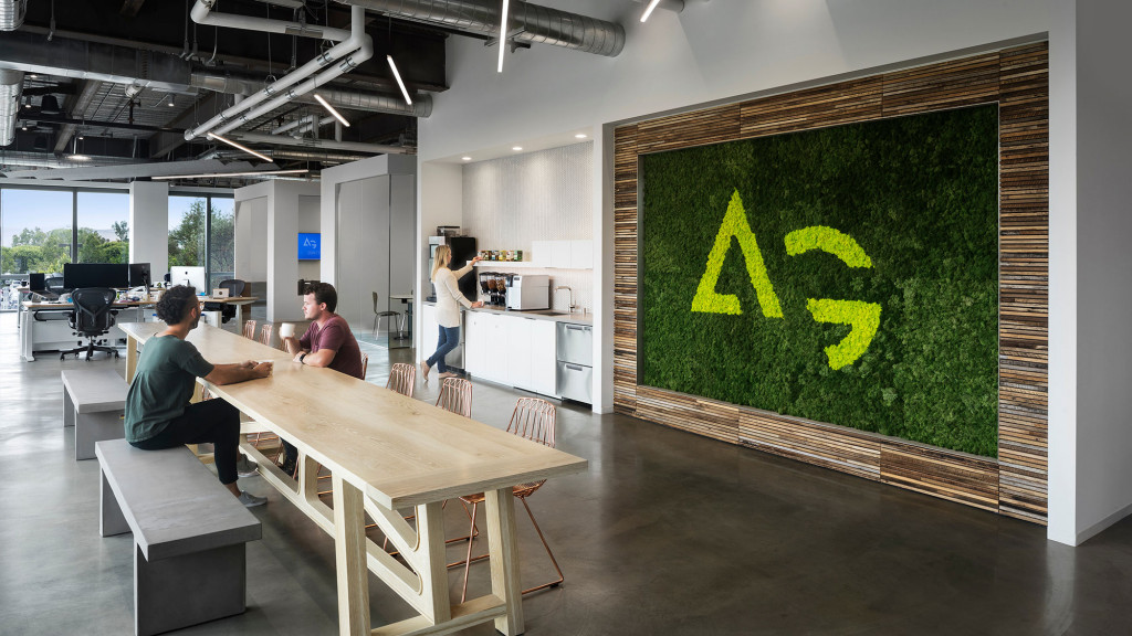 A couple of people sitting at a table in a room with a large screen.