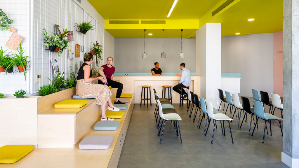 A group of people sitting in a room with chairs and tables.