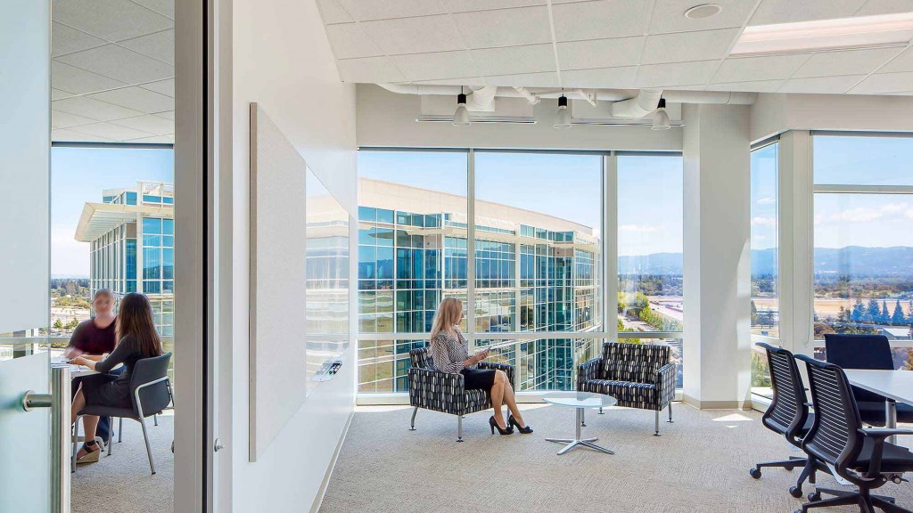 A couple of women sitting at a table in a room with large windows.