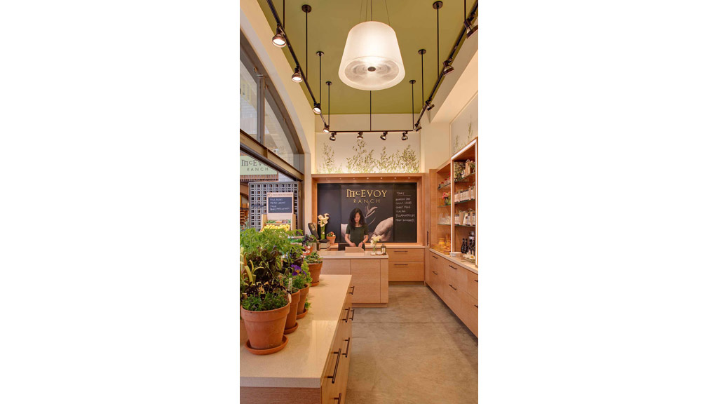 A person standing in a room with plants and a counter.