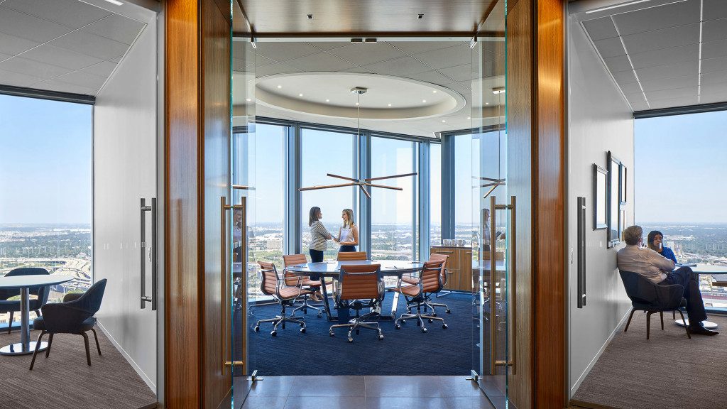 A group of people sitting at a table in a room with large windows.