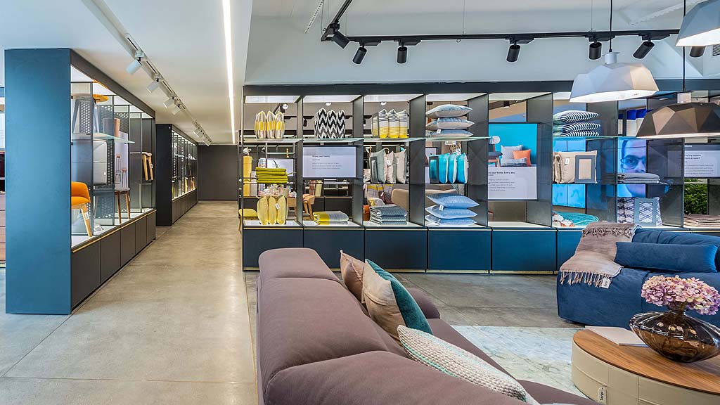 A room with a couch and a counter with a display of electronic devices.