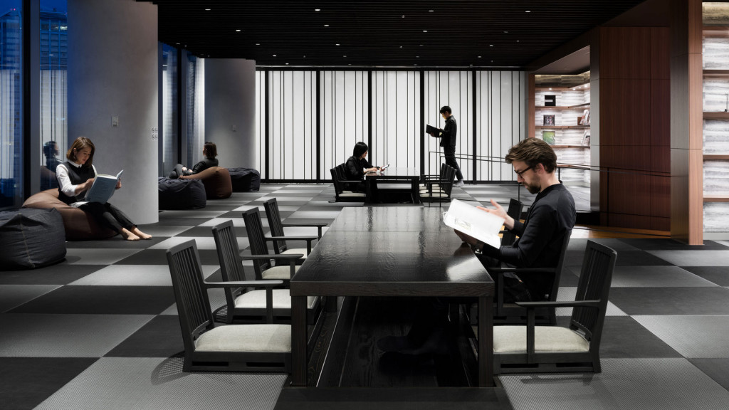 A group of people sitting in a room with a table and chairs.