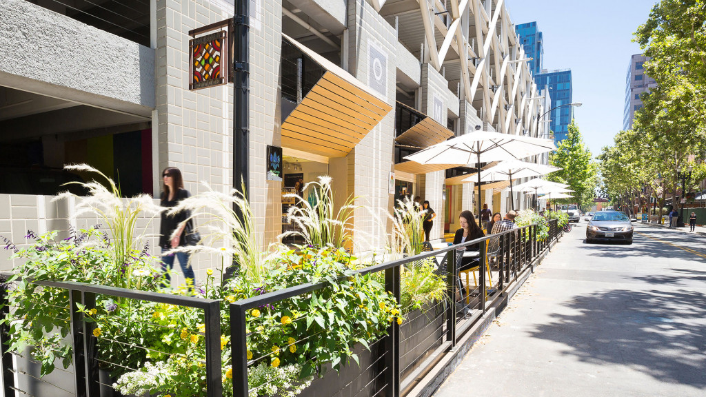 A street with a row of buildings and people walking on it.