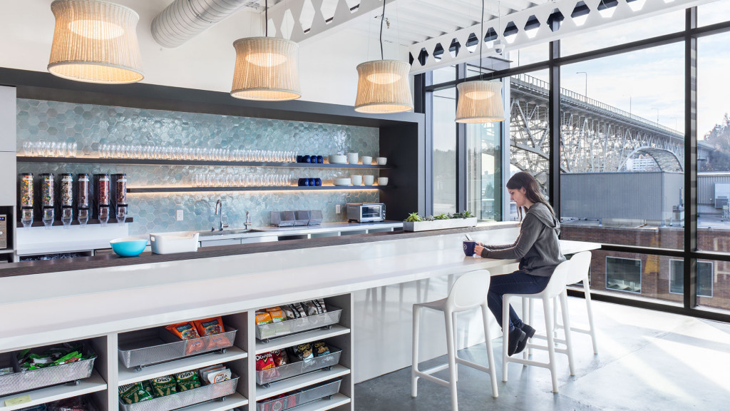 A person sitting on a stool in a room with shelves of bottles.