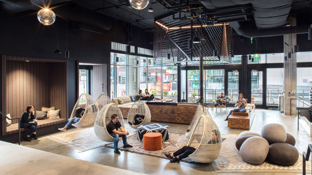 A group of people sitting on a couch in a room with large windows.