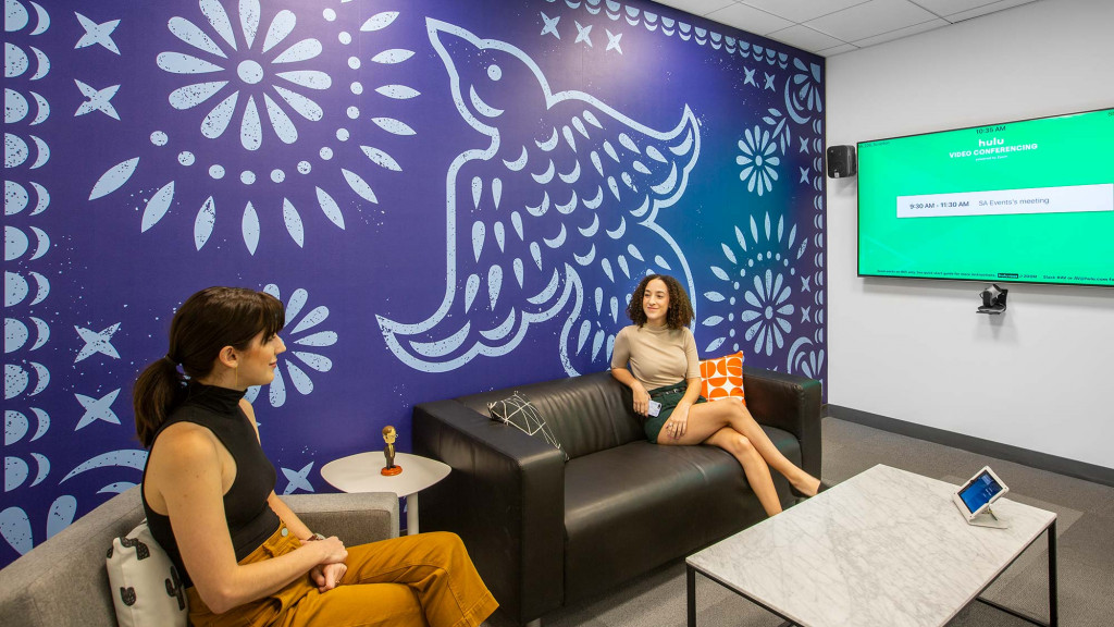 A person and a child sitting on a couch in a room with a map on the wall.