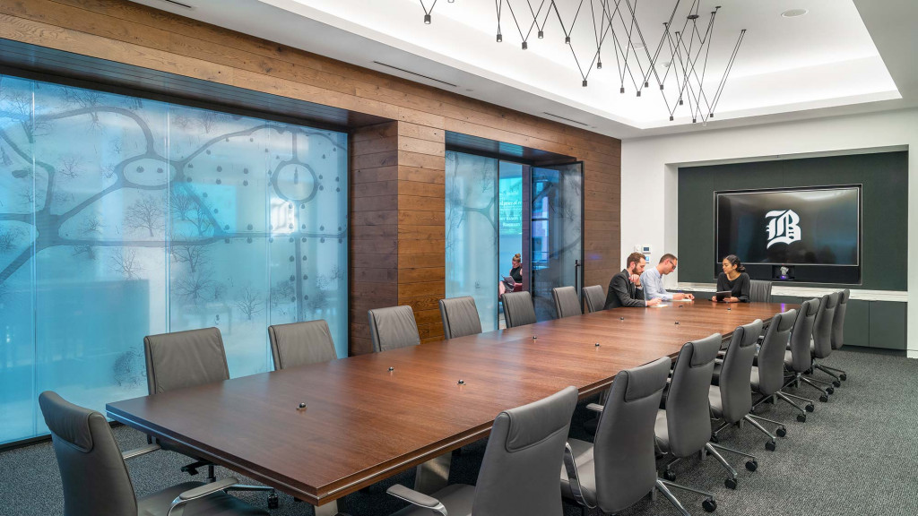 A group of people sitting at a table in front of a large screen.
