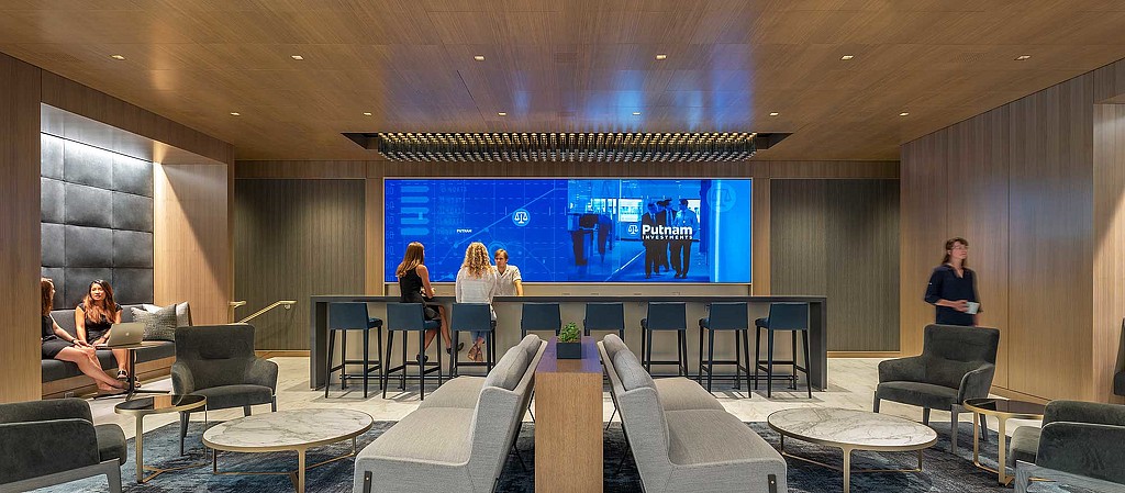 A group of people sitting in a room with a large screen.