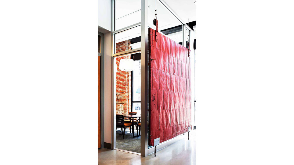 A red door with a table and chairs in front of it.