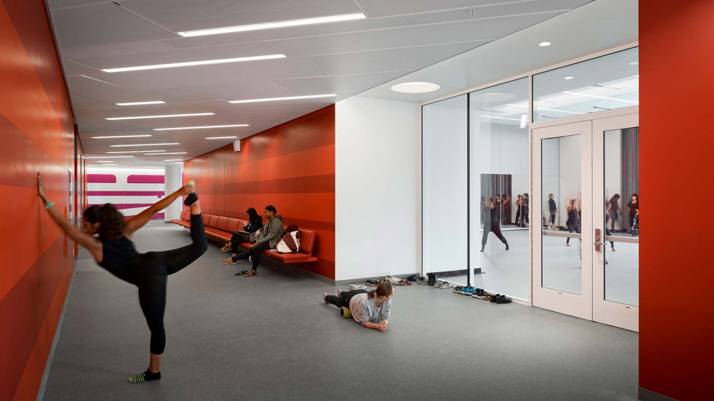 A person doing a handstand in a room with other people.