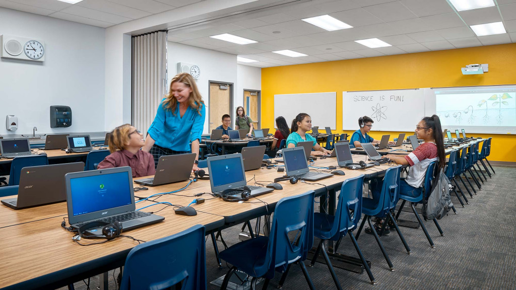 A group of people sitting at a table with laptops.