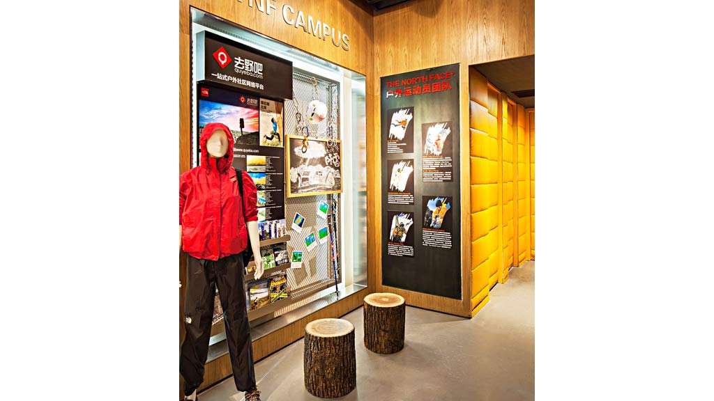 A person in a garment standing in front of a sign.