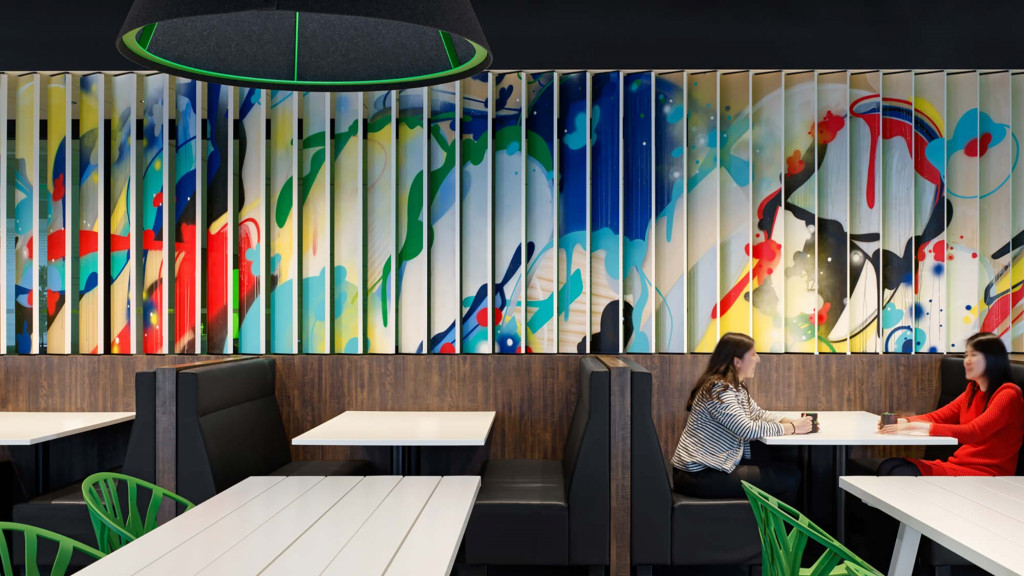 A couple of women sitting at a table in front of a colorful wall.