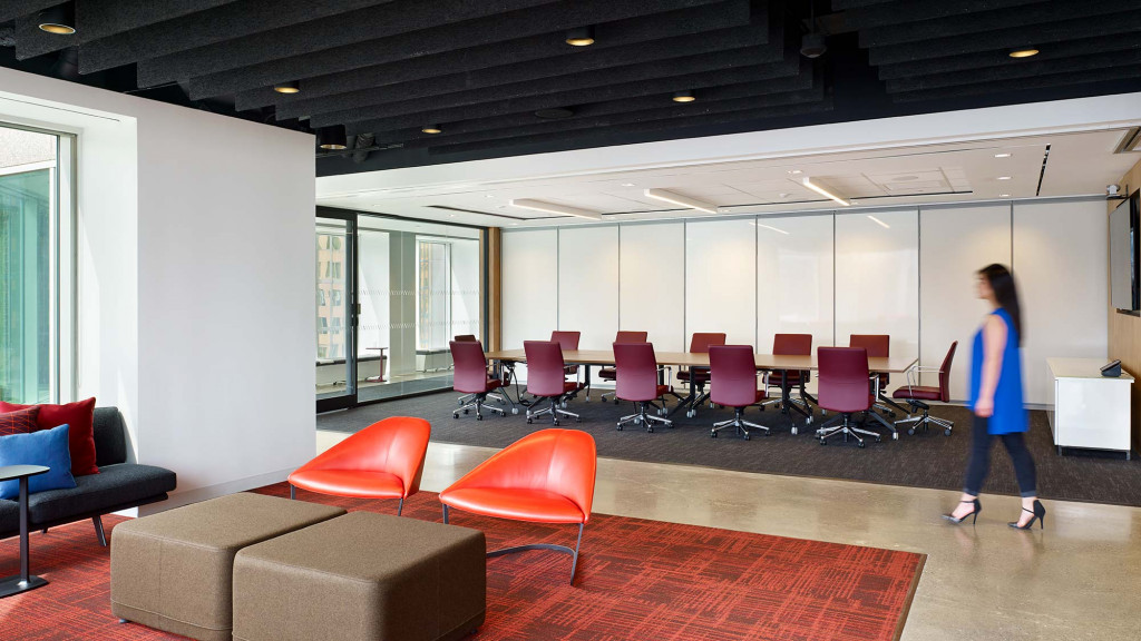 A person walking in a room with red chairs and a red carpet.