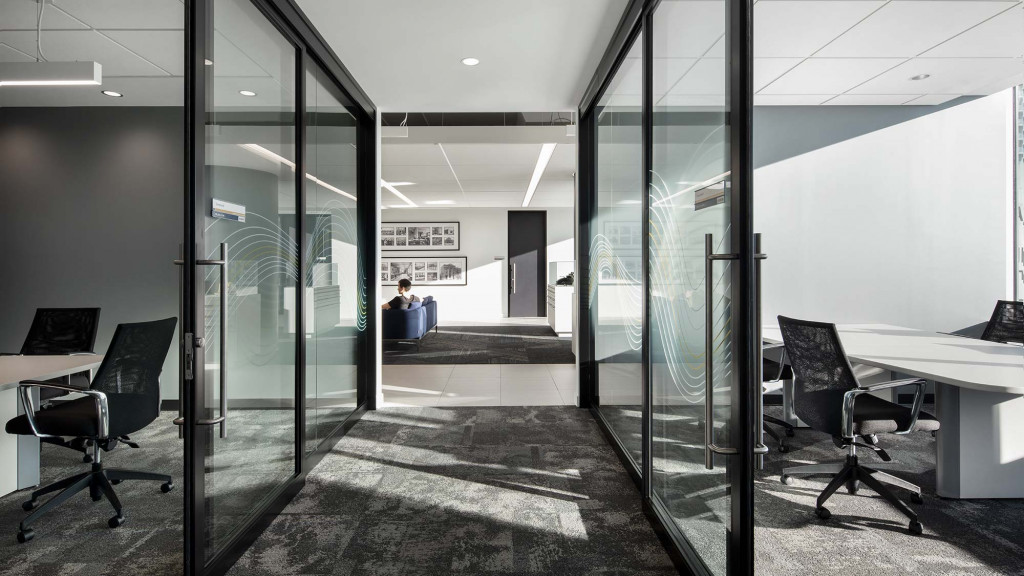 A room with glass walls and a desk with a computer.