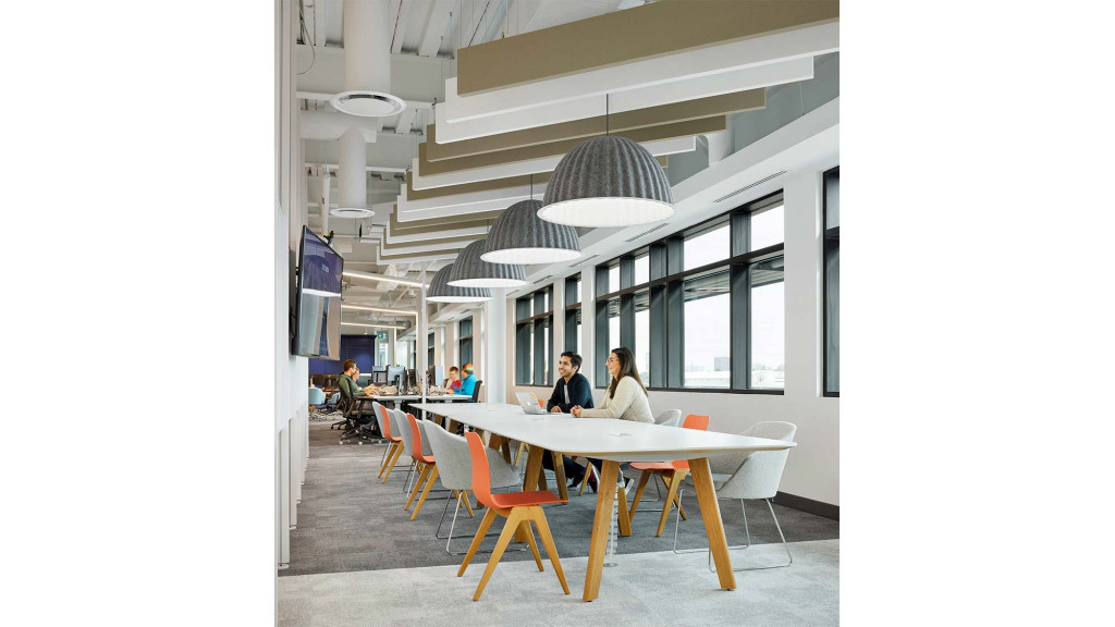 A group of people sitting at a table in a room with a staircase.