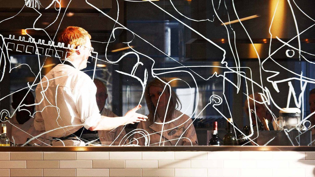 A man and woman sitting at a table with a screen with lights.